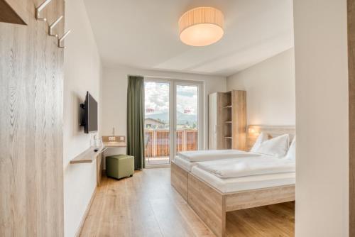 Schlafzimmer mit einem Bett und einem Fenster in der Unterkunft COOEE alpin Hotel Kitzbüheler Alpen in Sankt Johann in Tirol