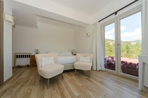 a bedroom with a bed and two chairs and a window at Relais Chalons d’Orange in Pescasseroli