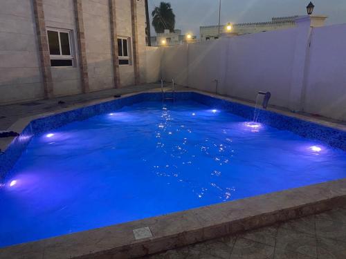 una gran piscina de agua azul con luces. en Al Noor Plaza en Salalah