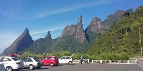 um parque de estacionamento com carros estacionados em frente a uma montanha em Conjugado Aconchegante em Teresópolis em Teresópolis