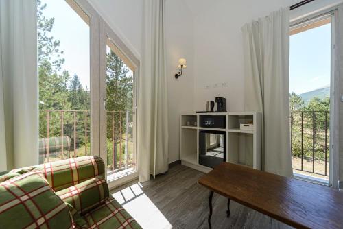a living room with a table and two large windows at Relais Chalons d’Orange in Pescasseroli