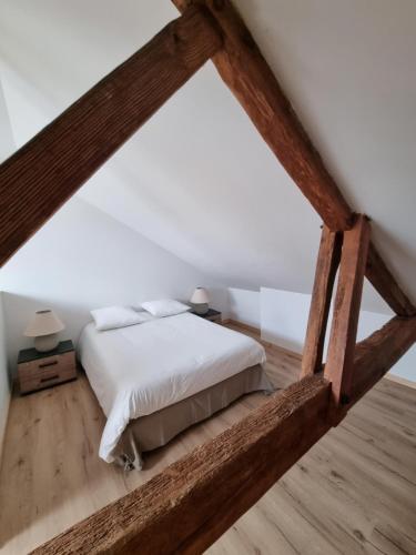 um quarto com uma cama com lençóis brancos e pisos em madeira em Le Crocolion em Arès