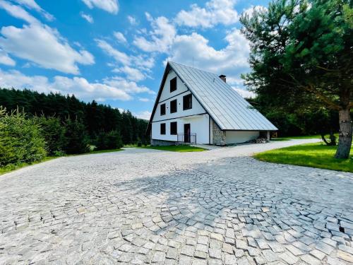 a cobblestone driveway with a white barn at Villa Pinus Slovenský raj - Hotel Čingov dependance in Smižany