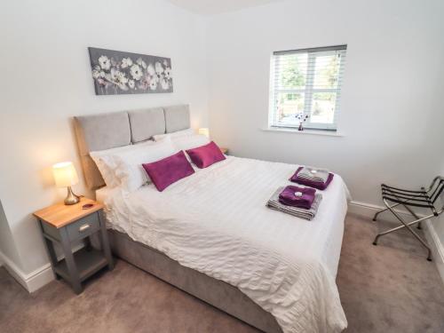 a bedroom with a large white bed with purple pillows at The Old Bakery, Apartment 5 in Shipston-on-Stour