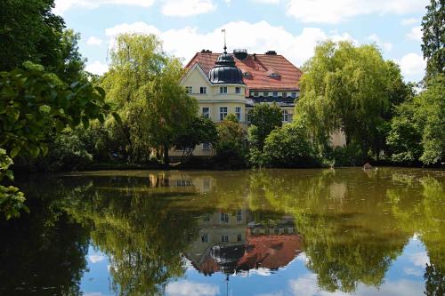 a building with a reflection in a lake at Schloss Mörlbach in Icking