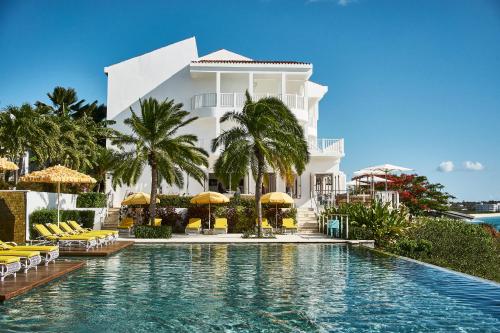 uma piscina em frente a um edifício branco em Malliouhana Resort Anguilla em Meads Bay