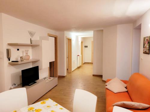sala de estar con sofá naranja y sillas blancas en Appartamento Rosina, per 4/6 persone. In centro, en Coredo