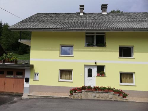 una casa gialla con dei fiori davanti di Apartment Jalen a Bohinjska Bela