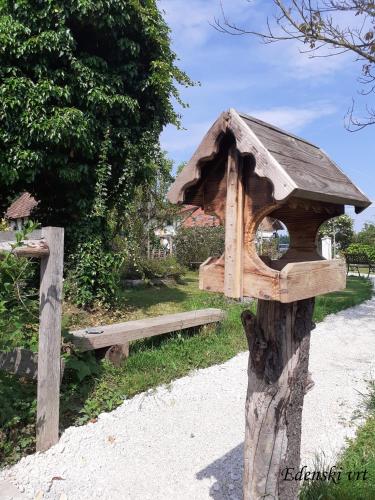 a wooden bird house on a tree stump with a bench at Edenski vrt in Ivančna Gorica