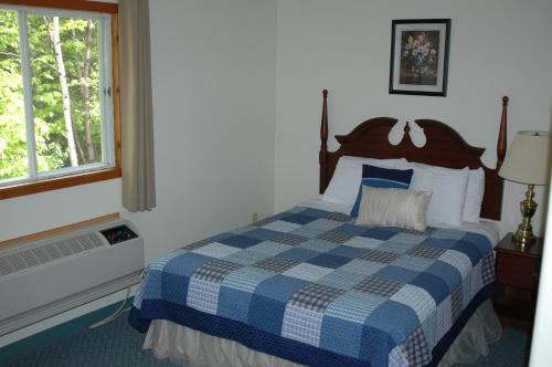 a bedroom with a blue and white bed with a window at Admiral Digby Inn Restaurant and Cottages in Digby