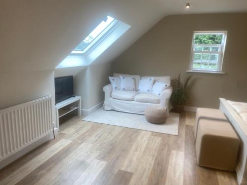 a living room with a white couch and a skylight at Nettleford in Kelsall
