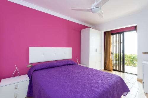 Dormitorio púrpura con cama y ventana en Calma House .Golf&Sail - Sea and port view, en San Miguel de Abona