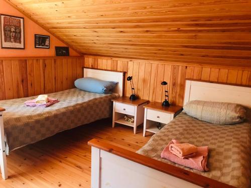 2 łóżka w pokoju z drewnianymi ścianami w obiekcie Ferienhaus Anders w mieście Terjärv