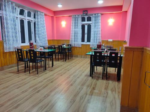 拉沖的住宿－The Lachung Inn，用餐室配有桌椅和粉红色的墙壁