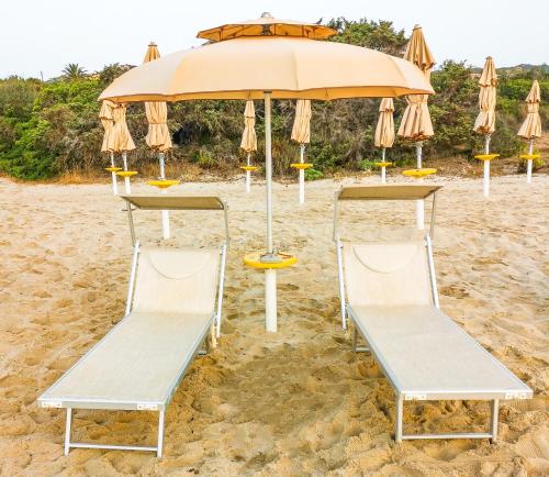 un gruppo di sedie e un ombrellone in spiaggia di "SARDESIDENCE" Spiaggia Privata WiFi Parcheggio Riservato a Costa Rei