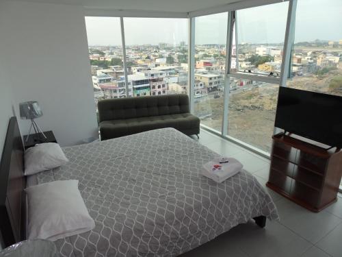 1 dormitorio con cama, sofá y ventana grande en 1340 Quo Habitación en Lujoso Departamento a 1 minuto del Aeropuerto, en Guayaquil