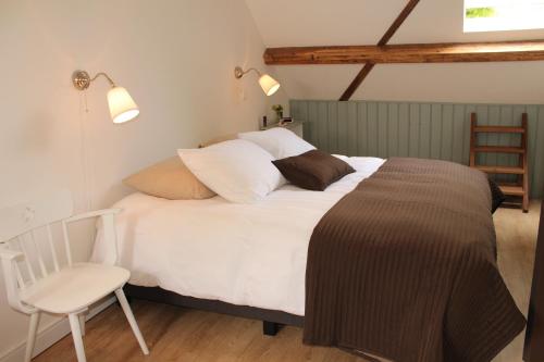 ヌエネンにあるBed & Breakfast Langlaarの白いベッドと椅子のある寝室