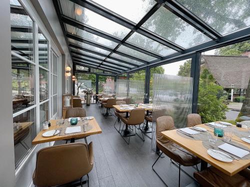 a restaurant with wooden tables and chairs and windows at Hotel du Nord, Hamburg-Volksdorf in Hamburg