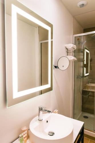 a bathroom with a sink and a mirror and a shower at Best Western Plus Le Havre Centre Gare in Le Havre