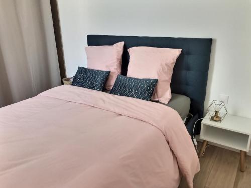 a bedroom with a large bed with pink sheets and pillows at Villa Bellenbois avec piscine privée , proche La Rochelle in Sainte-Soulle