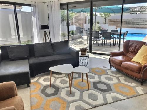 a living room with a black leather couch and tables at Villa Exceptionnelle Piscine et Jardin privé Séjour Haut de gamme proche La Rochelle in Sainte-Soulle