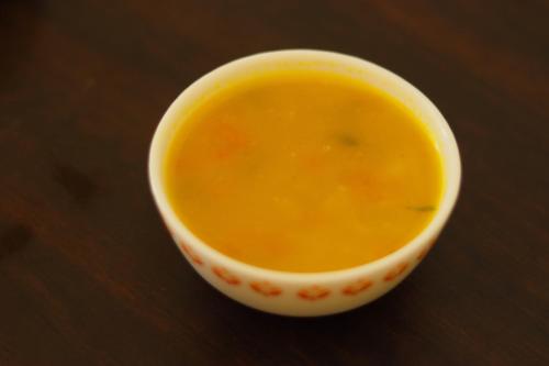 a cup of yellow soup sitting on a table at Hotel Sahil Inn in Mandarmoni