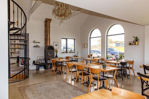 un restaurante con mesas y sillas de madera y ventanas en Magma Hotel en Kirkjubæjarklaustur