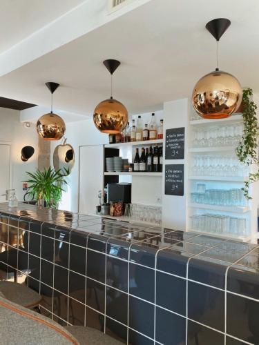 a counter in a restaurant with pendant lights at Hôtel Le Collonges TV connecté wifi Netflix in Brive-la-Gaillarde