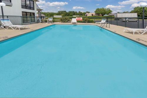 a large blue swimming pool with chairs and tables at Days Inn by Wyndham Sanford in Sanford