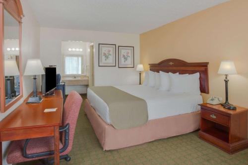 a hotel room with a bed and a desk and a computer at Days Inn by Wyndham Asheville West in Candler