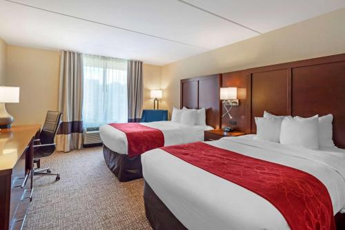 a hotel room with two beds and a desk at Comfort Suites Fredericksburg North in Fredericksburg
