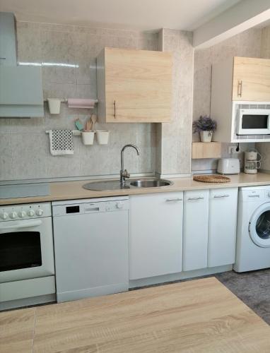 a kitchen with white cabinets and a sink and a dishwasher at Apartamento Bornos&Huesca in Huesca