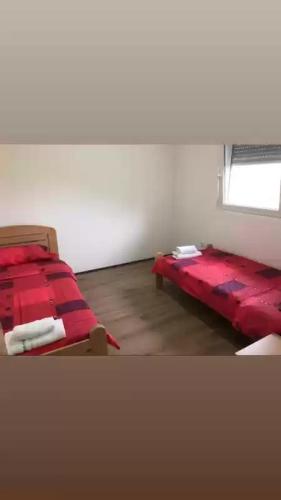 um quarto com duas camas vermelhas e uma janela em Smestaj sobe di camera uno em Subotica