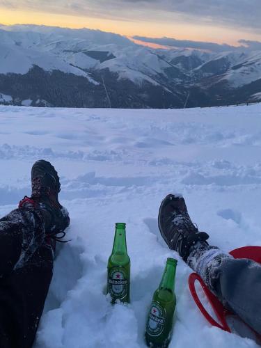 une personne assise dans la neige avec deux bouteilles dans l'établissement Au pied des pistes, à Saint-Aventin