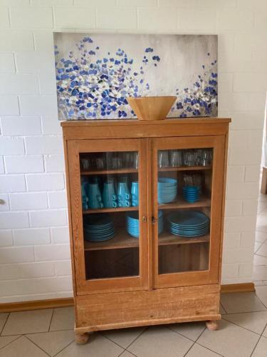 a wooden cabinet with blue dishes in it at Marie Carla in Simonsberg