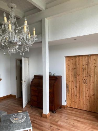 a living room with a chandelier and a wooden door at Marie Carla in Simonsberg