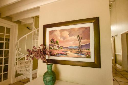 a painting on a wall with a vase with flowers at Waterford House in Clarens