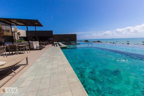 - une piscine avec de l'eau bleue, des tables et des chaises dans l'établissement Holandas Prime - Flat 722, à João Pessoa