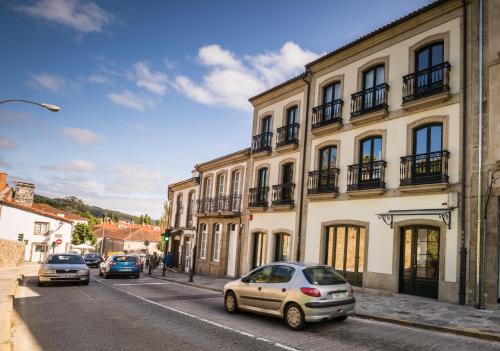 a street with cars parked in front of buildings at Hotel Pombal Rooms in Santiago de Compostela