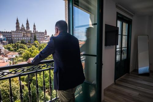 a man standing in front of a window looking out at Pombal Rooms Santiago in Santiago de Compostela