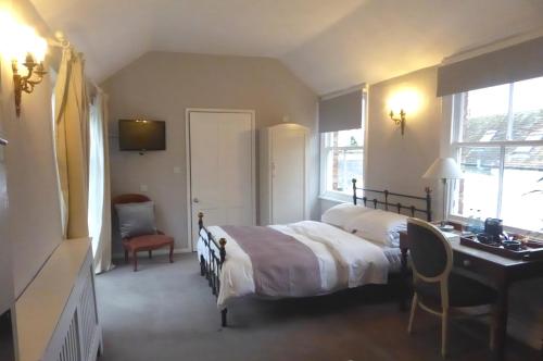 a bedroom with a bed and a desk and a desk at The Crown Inn, Kemerton in Tewkesbury