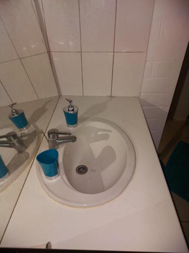 een witte wastafel in een badkamer met blauwe kopjes bij LÃCAZÈRĂ Sãfãrì in Mamoudzou