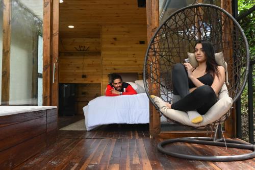 a woman sitting in a wicker swing in a bedroom at Ecohotel Portillo de San Bernardo in Nocaima