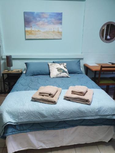 ein Schlafzimmer mit einem blauen Bett und Handtüchern darauf in der Unterkunft KOL-IN SELF CATERING in Prieska
