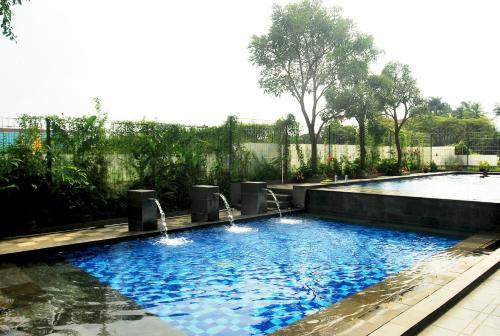 a swimming pool with two fountains in a yard at High Livin Apartment Baros in Cimahi