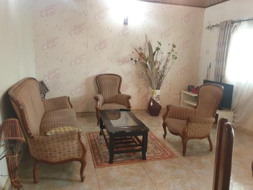 a living room with three chairs and a table at Résidence La ROSÉE in Yaoundé