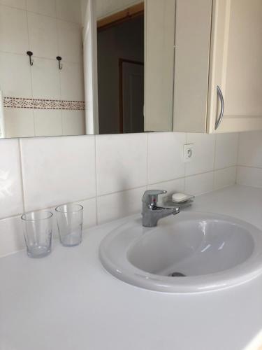 a bathroom sink with a mirror and two glasses on it at appartement in de Haute Savoie (Saint Jean de Sixt) in Saint-Jean-de-Sixt