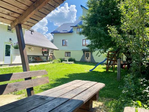 a wooden bench in a yard with a house at Medova Hata in Verkhnyaya Rozhanka