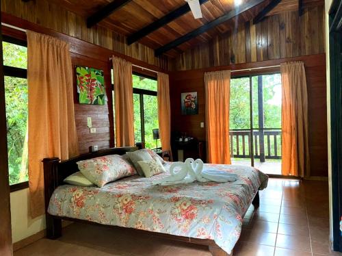 a bedroom with a bed in a room with windows at Heliconias Rainforest Lodge in Bijagua