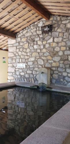 une piscine avec un mur en pierre et une fontaine dans l'établissement Lou Camillou, à Valvignères